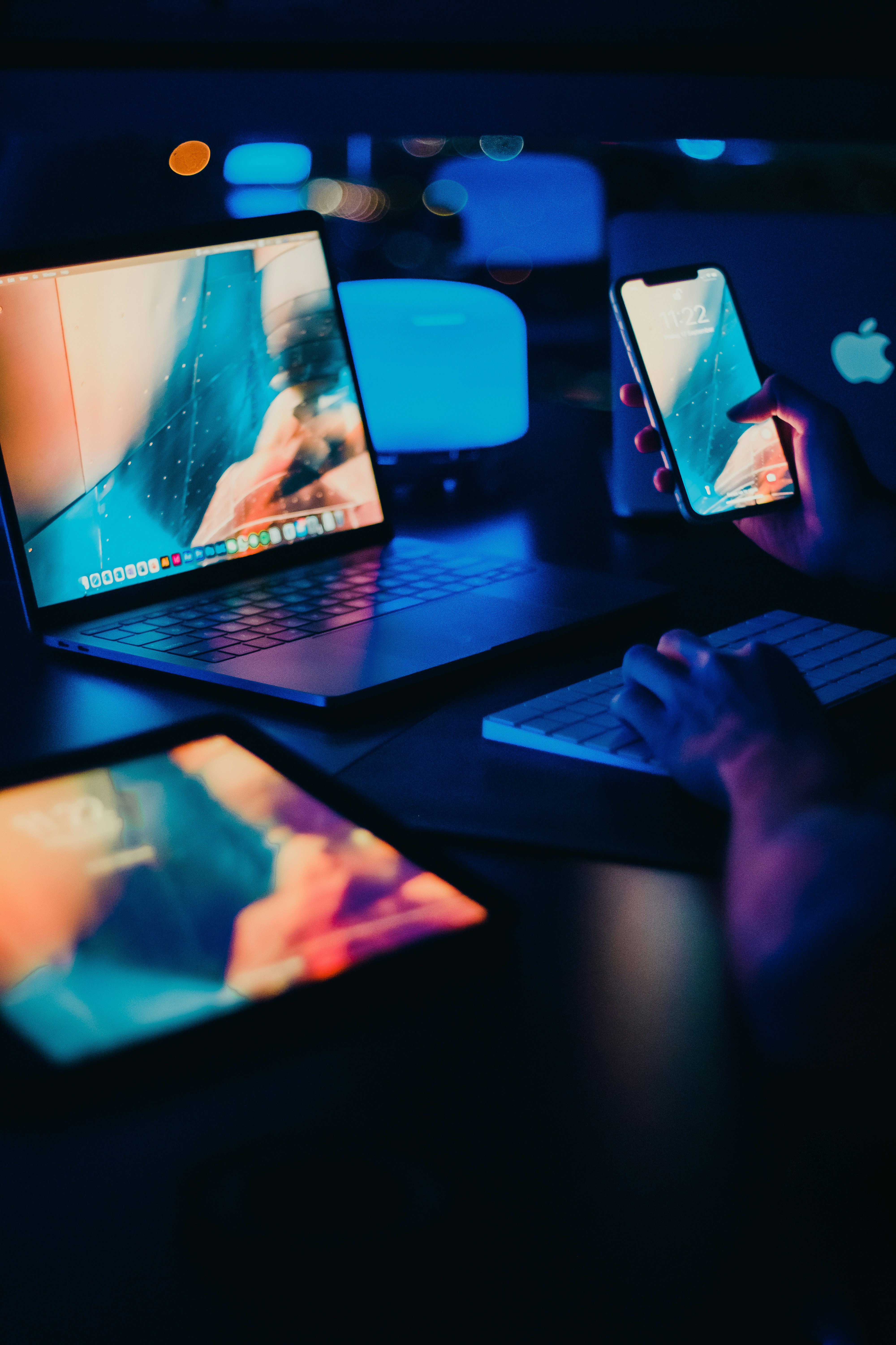 Multiple digital devices emitting blue light in a dark room, showing common sources of blue light exposure