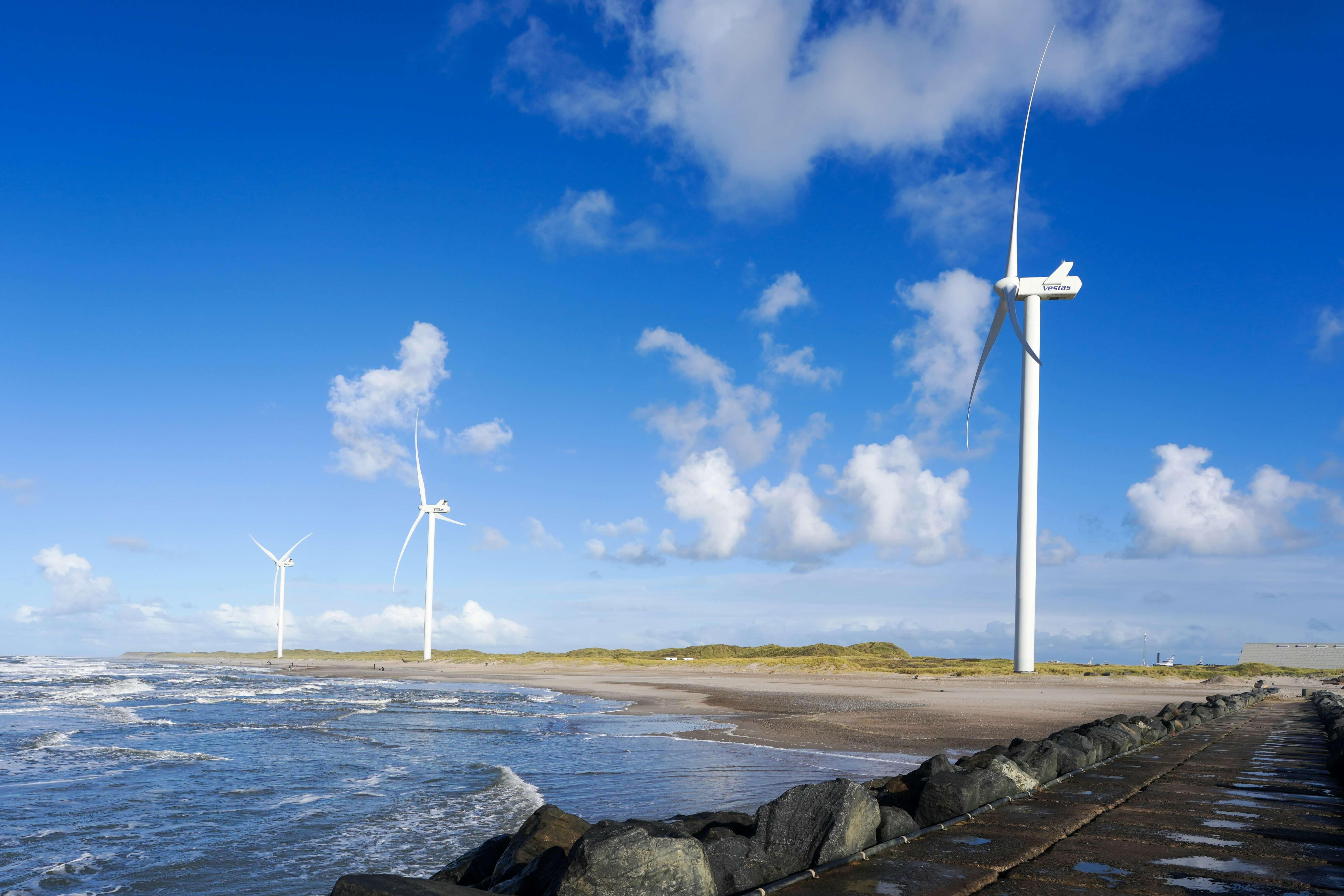 Coastal wind turbines and shoreline under a clear sky