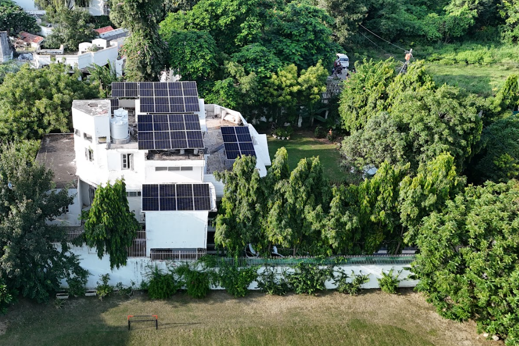 Aerial view of a residential home with a rooftop solar array surrounded by trees, a real Solarise zero-upfront installation